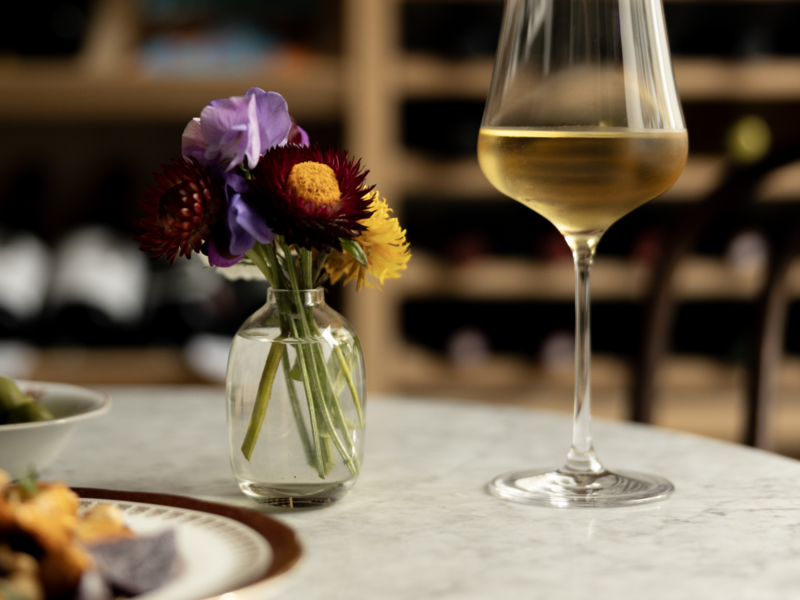 Redwood Wines, Dunkeld, Scotland — close-up of marble table with seasonal flowers, white wine glass and elegant plating — Scotland regional winner, Best Local Restaurant 2025 in The Good Food Guide. Photo by Alexander Baxter.